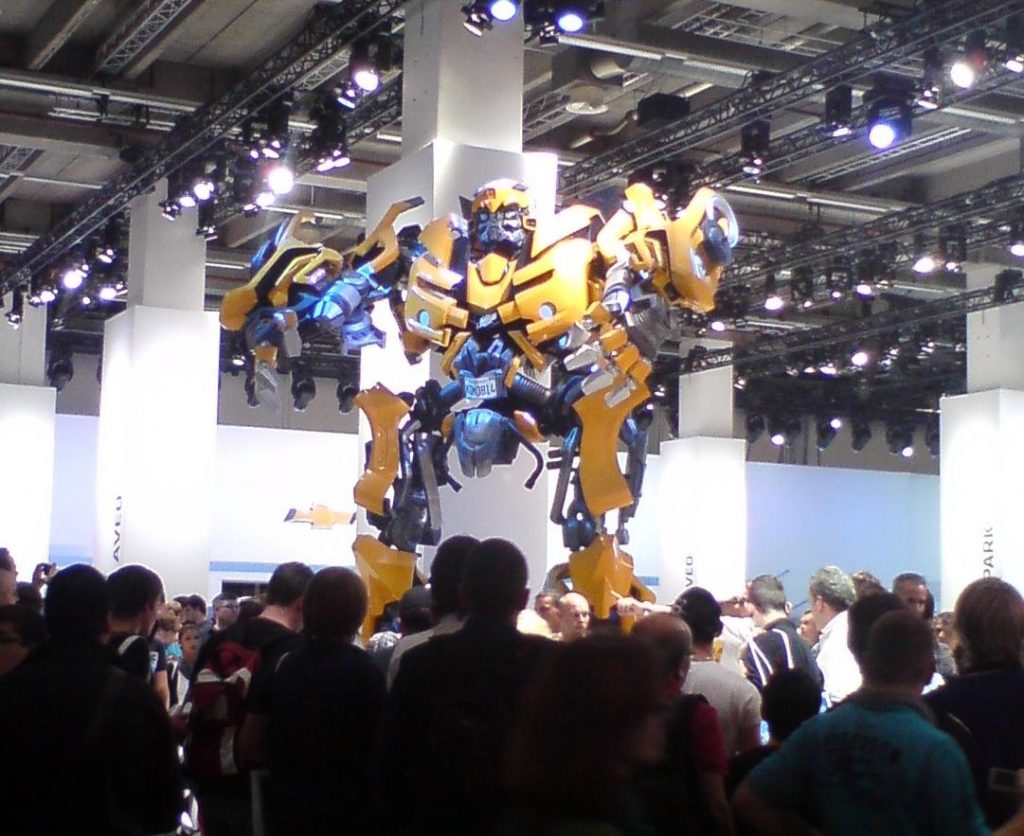 Ein Transformer in Gelb und Violett wird vor einem großen Publikum ausgestellt