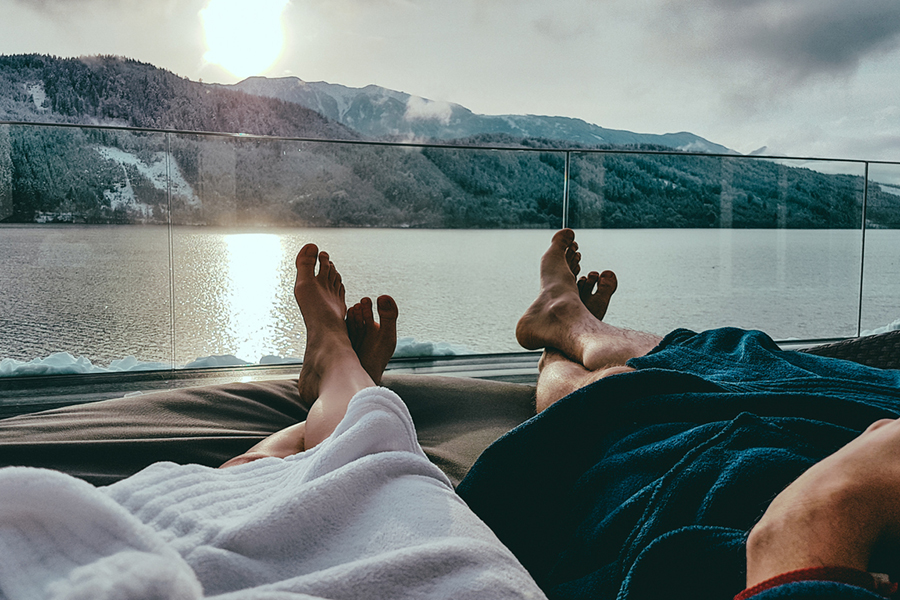 Füße und Beines eins Paars, das im Urlaub auf einen Bergsee guckt